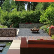 Terrasse mit großformatigen Platten, Kiesfläche und Bambushecke mit Loungemöbeln