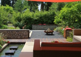 Terrasse mit großformatigen Platten, Kiesfläche und Bambushecke mit Loungemöbeln