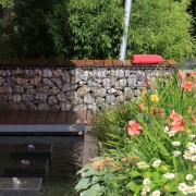 Gabionen als Sitzmauer mit einem Wasserspiel und quadratischen Quellsteinen