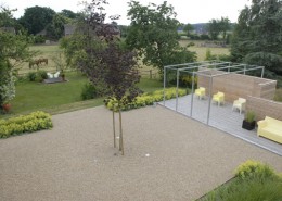 Kiesflächen mit Holzterrasse, Frauenmantel und Sichtschutzwand