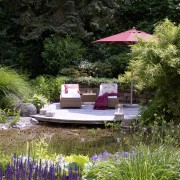 romantisches Holzdeck am Gartenteich mit Natursteinmauer