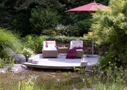 romantisches Holzdeck am Gartenteich mit Natursteinmauer