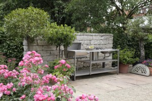 Outdoor-Küche aus Edelstahl vor gartenmauer aus Naturstein