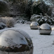 Edelstahlkugeln als Skulptur liegen im sommer und Winter auf dem Rasen