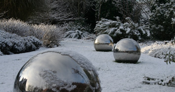 Edelstahlkugeln als Skulptur liegen im sommer und Winter auf dem Rasen